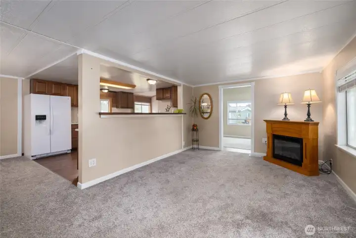 The view that greets you upon entering includes the front living room, the doorway to the family room, and the eat-in kitchen bar.  The electric fireplace conveys with the property.