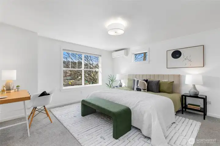 Spacious primary suite featuring abundant natural light (western exposure here as well) and a dedicated mini split system for efficient cooling during warmer months. King bed shown with plenty of additional space.