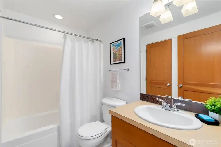 Upper-level full bath with neutral finishes and a well-sized vanity offering excellent storage. Door leads to hot water heater/boiler system.