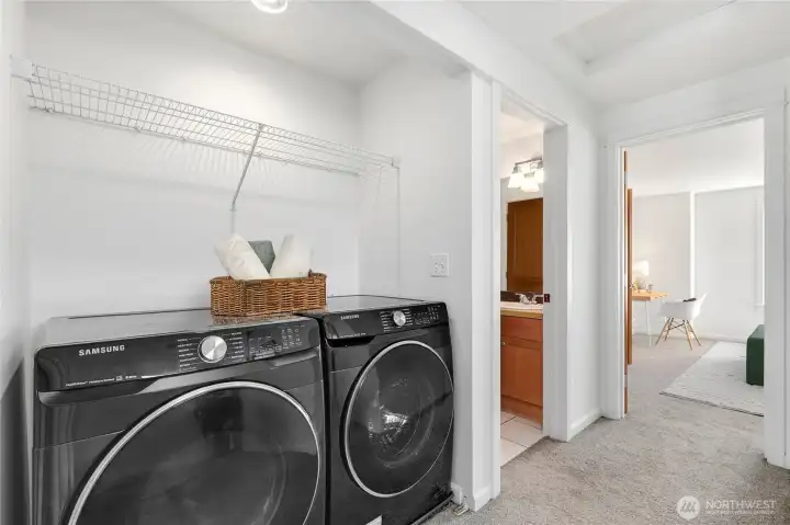 Dedicated laundry area with full-size washer and dryer and additional shelving for storage.