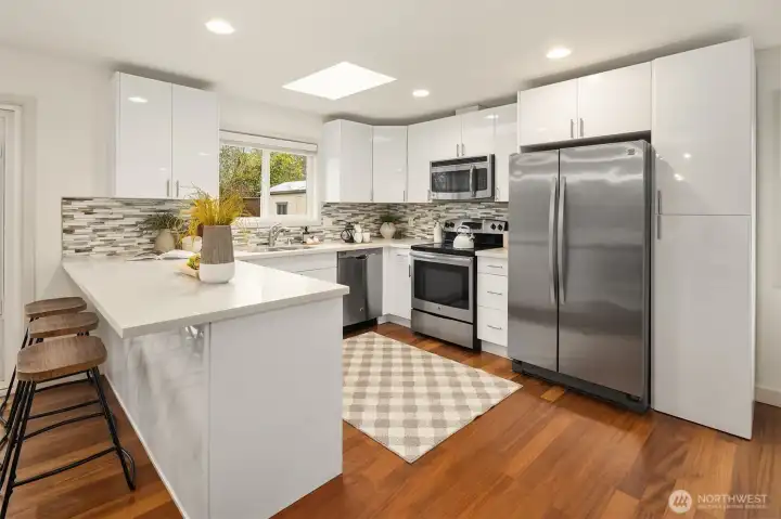 The updated kitchen pairs clean, timeless design with modern utility, featuring designer cabinetry, white quartz countertops, custom backsplash, and stainless steel appliances.