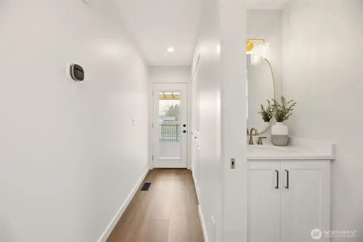 You don't appreciate it until you experience it. The main-level, fully remodeled powder bath is set away from the living room and kitchen. At the end of the hall is the new custom door leading to the deck and yard. Behind here is the door to the big garage.
