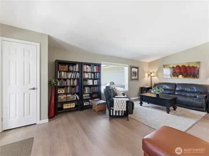 Bright and spacious living room with vaulted ceilings, luxury vinyl plank flooring, and abundant natural light.