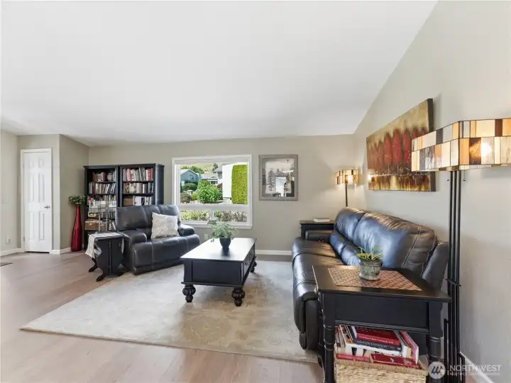 Bright and spacious living room with vaulted ceilings, luxury vinyl plank flooring, and abundant natural light.