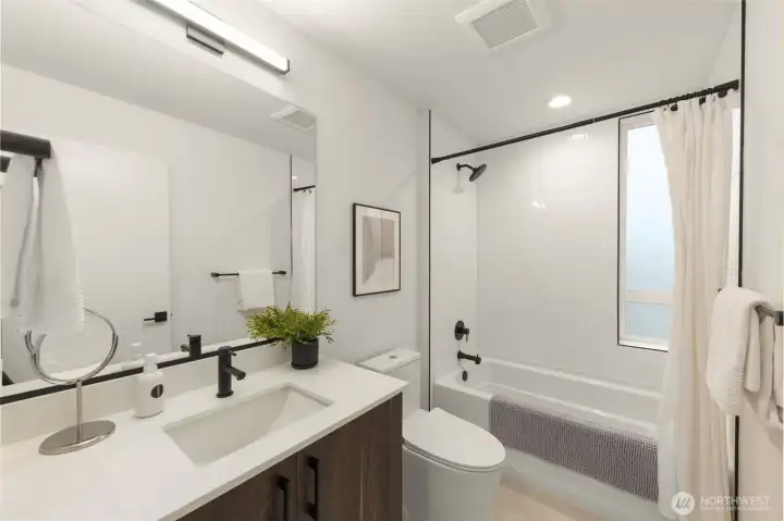 The secondary bathroom showcases meticulous craftsmanship, featuring a clean vanity and a beautifully tiled tub-to-ceiling surround. The secondary bathroom showcases meticulous craftsmanship, featuring a clean vanity and a beautifully tiled tub-to-ceiling surround.