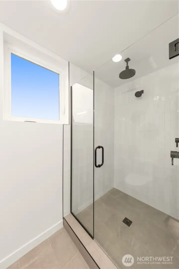 An upscale, glass-enclosed walk-in shower features floor-to-ceiling tile work and premium fixture selections. An upscale, glass-enclosed walk-in shower features floor-to-ceiling tile work and premium fixture selections.