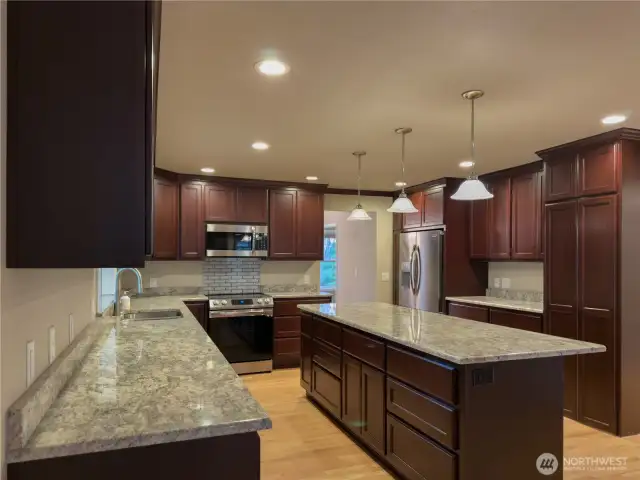 Beautiful chefs kitchen with full height cabinets, granite slab countertops, giant island & HIDDEN walk in pantry!