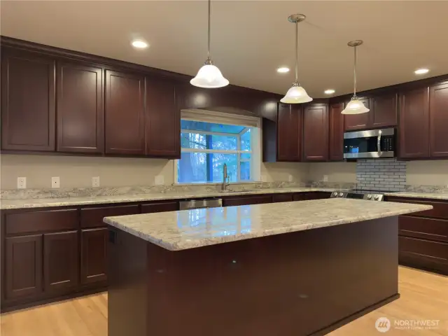 Beautiful chefs kitchen with full height cabinets, granite slab countertops, giant island & HIDDEN walk in pantry!