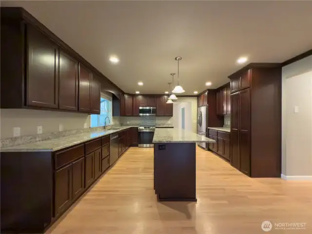 Beautiful chefs kitchen with full height cabinets, granite slab countertops, giant island & HIDDEN walk in pantry!