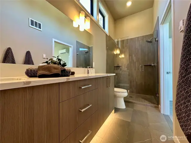 Primary bath with double vanity, undercab motion activated lighting, fully tiled shower and tall windows for great light