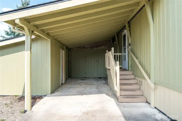 driveway with covered parking and two storage sheds