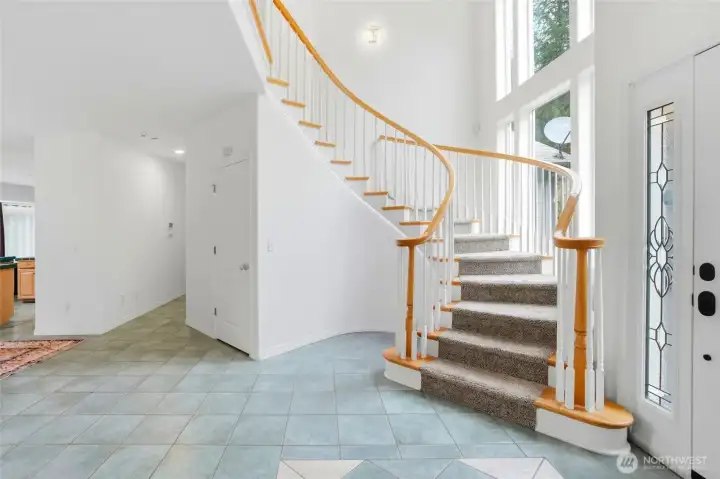 The grand two-story entry makes an unforgettable first impression with its dramatic spiral staircase and soaring ceilings. Natural light pours through the open space, creating an atmosphere that feels both elegant and welcoming.