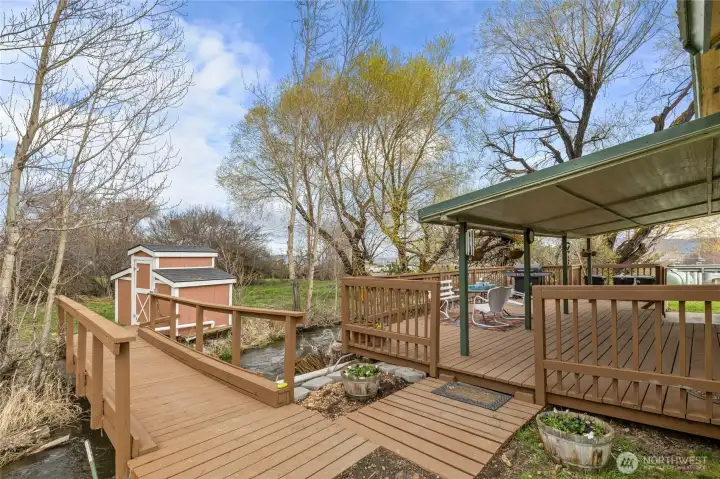 Enjoy the covered porch or stroll across the bridge to the other side of the property, featuring a firepit area and additional parking, including space for an RV.