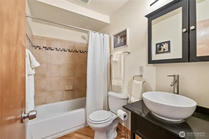 Downstairs full bath featuring a sleek tiled shower, a stylish sink/vanity, and modern finishes that add a touch of elegance.