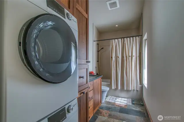 Stacked GE washer and dryer in the bathroom, where radiant in-floor heat continues for comfort and efficiency.