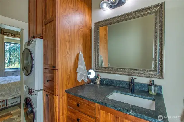 Bathroom features Moen fixtures with brass fittings, a soapstone countertop, and custom cabinetry with soft-close drawers and built-in hamper—combining quality and function.