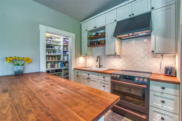 Walnut butcher block countertops, a small walk-in pantry, Sky River Industries kitchen cabinets with soft-close drawers and built-in storage, plus Café GE appliances—all combining to create a stylish and highly functional kitchen.