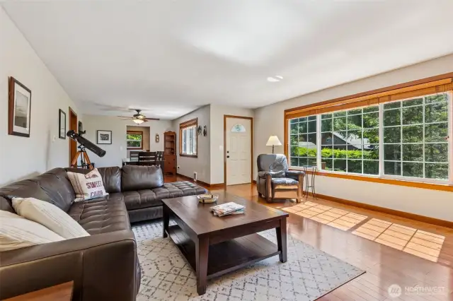 Looking back from living room to the front entry and dining room -- lots of natural lighting, hardwood floors, and a wood fireplace.