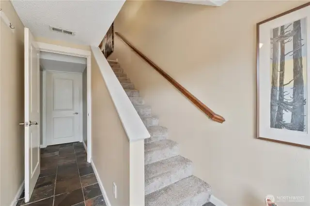 Tile entry leading to the large storage room straight ahead. Stairs go up to the 2nd level. To the left of the entrance to the storage room is the big family/rec room.