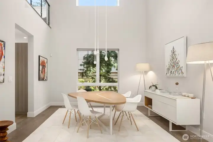 Dining space framed by double-height ceilings and sculptural lighting—simple, refined, and intentional.