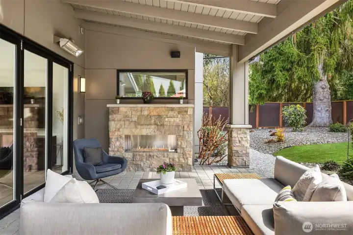 Seamless indoor-outdoor connection with covered seating, fireplace, infrared heaters, and year-round usability.