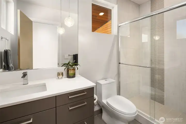 Additional bath with walk-in shower and streamlined, contemporary detailing.