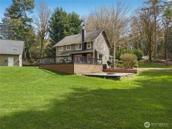 Attractive rear angle shows the deck, landscaped grounds, and peaceful privacy.