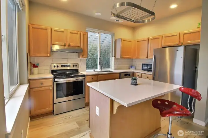 Kitchen with quartz counters & stainless steel appliances.