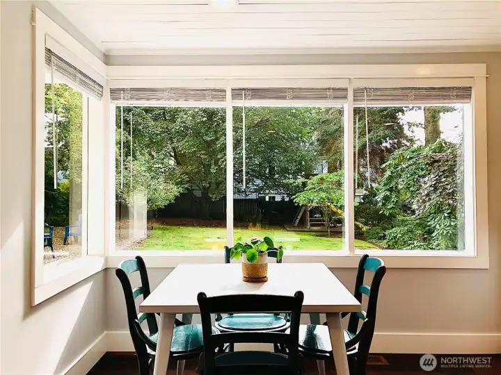 The kitchen eating area looks out into the large yard with mature plantings.
