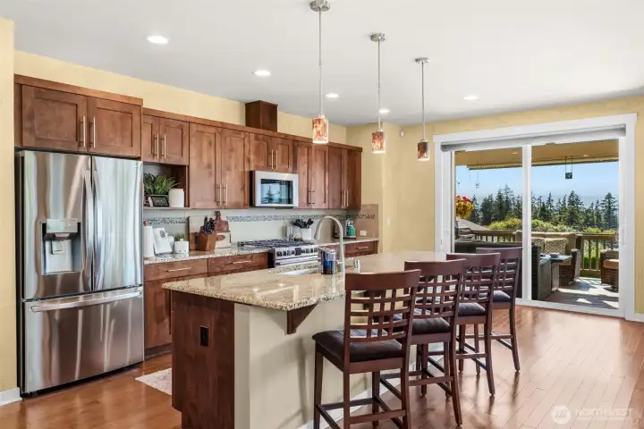 A delightful kitchen with an oversized island, custom soft closing cabinetry, newer stainless-steel appliances, and plenty of countertop food preparation space.