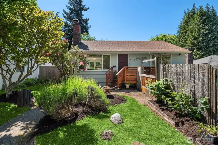 A classic 1948 Genesee Hill home tucked behind mature landscaping, with a rebuilt front deck, garage parking, and a welcoming garden approach.