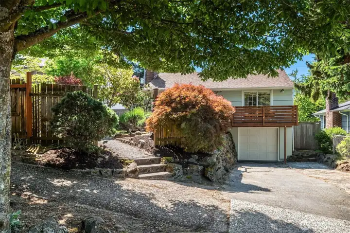 A beautiful screen of mature landscaping gives the home a tucked-away feel while still keeping it connected to the neighborhood. The home sits above the street with rock walls, layered plantings, and mature trees that create a rare sense of privacy before you even arrive at the front door.