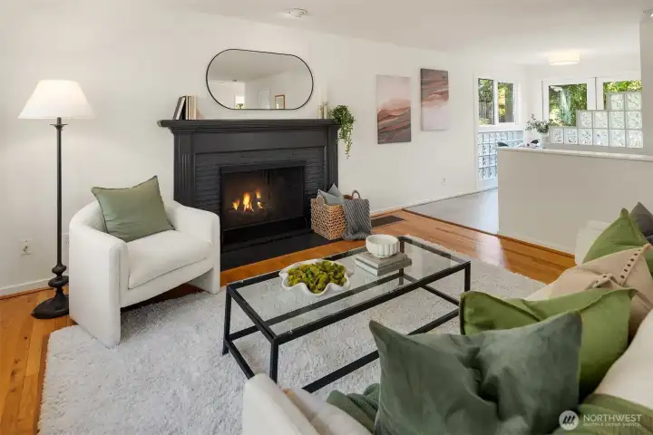 A wood-burning fireplace, hardwood floors, and soft natural light create a living room that feels warm, grounded, and instantly welcoming.