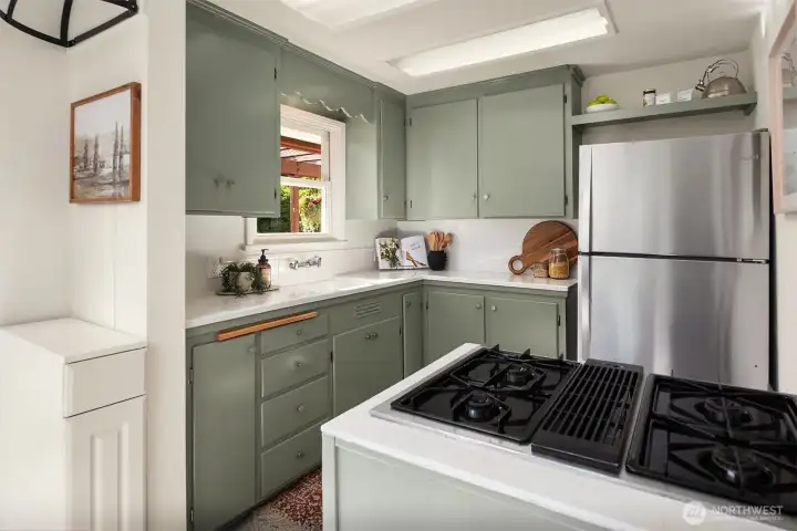 Freshly painted cabinetry, vintage charm, gas cooking, and garden views give the kitchen personality while staying true to the home’s character.