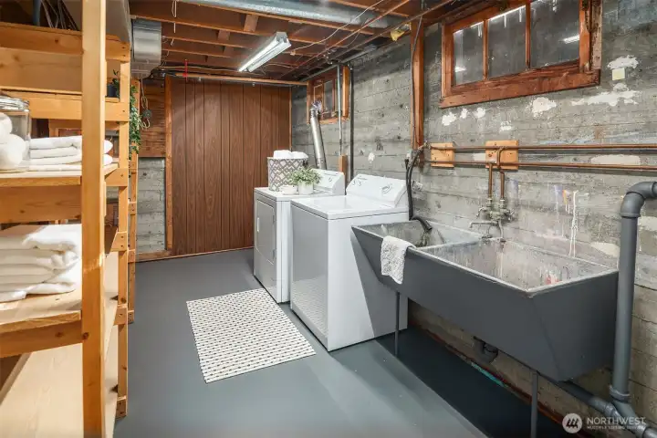 A clean, functional lower-level laundry area with utility sink, storage, and workspace — the kind of practical space every home needs but rarely gets to show off.