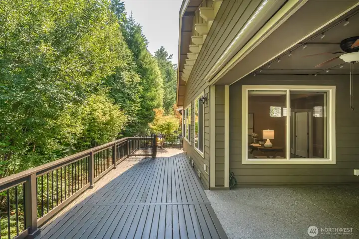The oversized covered patio with fireplace and motorized screens leads to the freshly painted deck overlooking the permanent greenbelt.