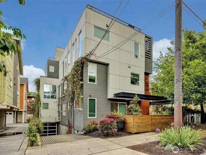 Contemporary townhouse community features modern architecture, lush greenery, and secure garage parking, all tucked into a vibrant urban neighborhood.