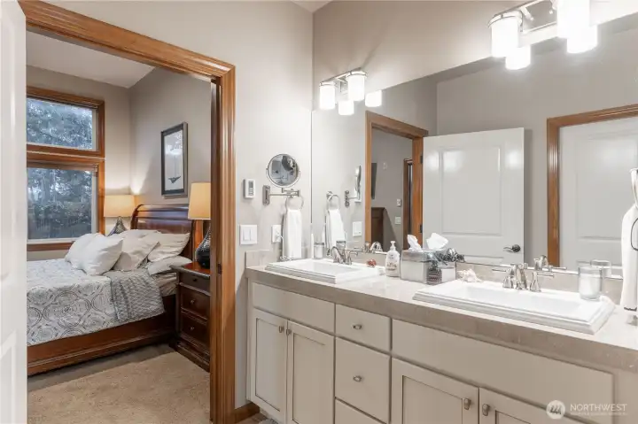 Primary bath has radiant floor heating. Note white cabinetry and double sinks.