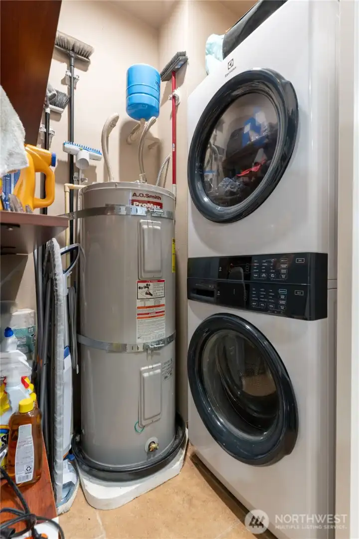 New 2024 stacking washer and dryer.  Utility/storage closet that also shows the hot water tank.  Just across the kitchen in the hallway.