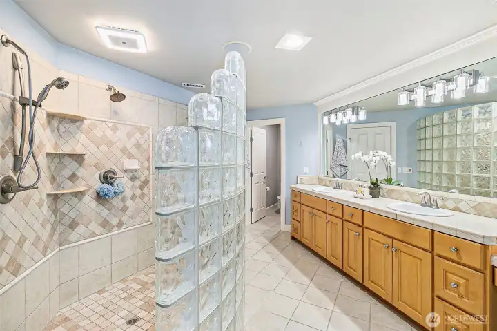 The primary bath is complete with a  custom glass walk-in shower and plenty of counterspace.