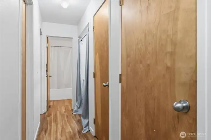 Hallway layout with utility closet (water heater and AC), additional storage closet, and in-unit washer and dryer. Bathroom straight ahead with two bedrooms located to the left.