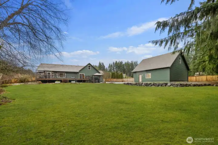 View across the spacious backyard highlighting the detached outbuilding and the home's elevated deck.