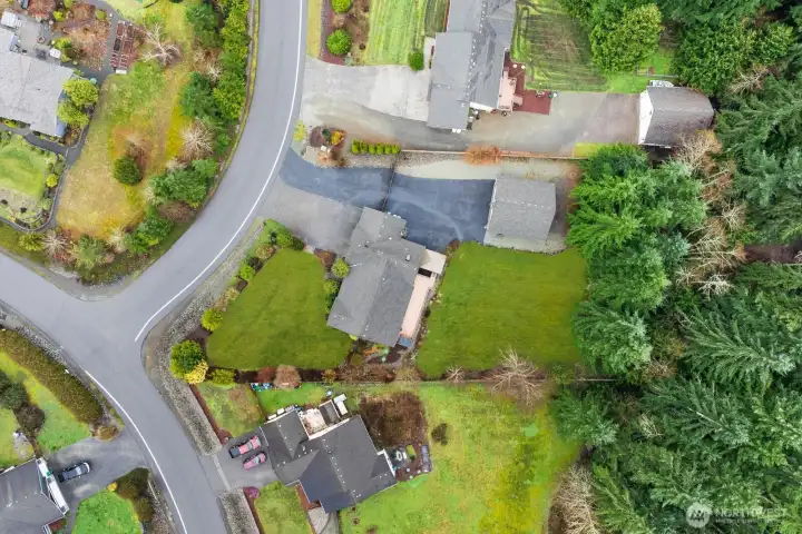 Overhead aerial view showing the home, detached shop, driveway layout, and surrounding yard space within the neighborhood.