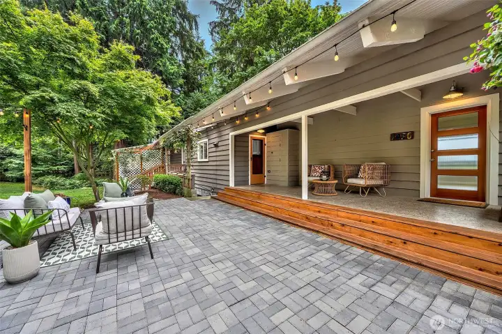 Covered porch entry and beautiful stone patio surrounded by tranquil yard.