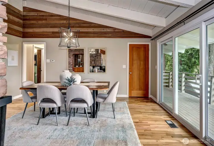 Dining room with open beam ceilings and slider to large deck for viewing sunsets.