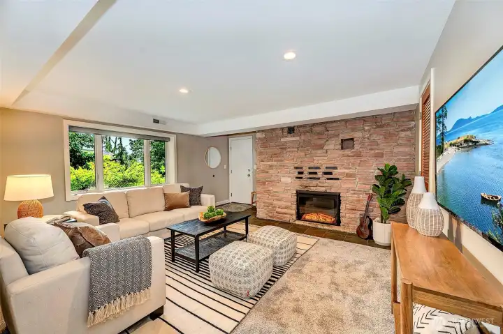 Daylight lower living room with electric fireplace. Door access to two car garage.