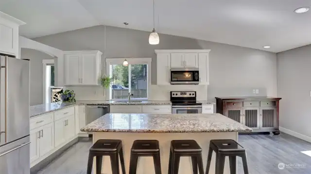 Kitchen boasts stainless steel appliances, granite countertops, and large island with seating.