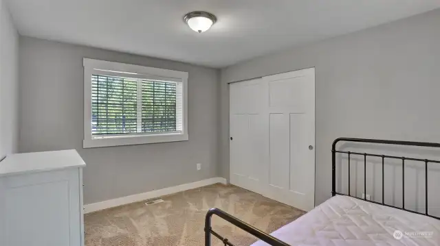 Guest bedroom with large window and sizable closet.