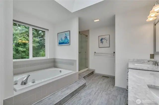 The primary bathroom window looks out to the green space beyond.