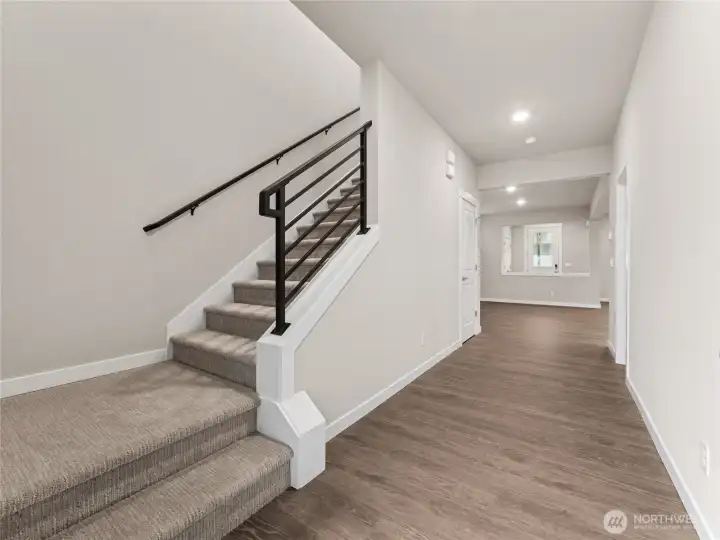 One of the main entry area with wide hallway and open metal railings.  Materials, colors, and finishes will vary. See site agent for details.